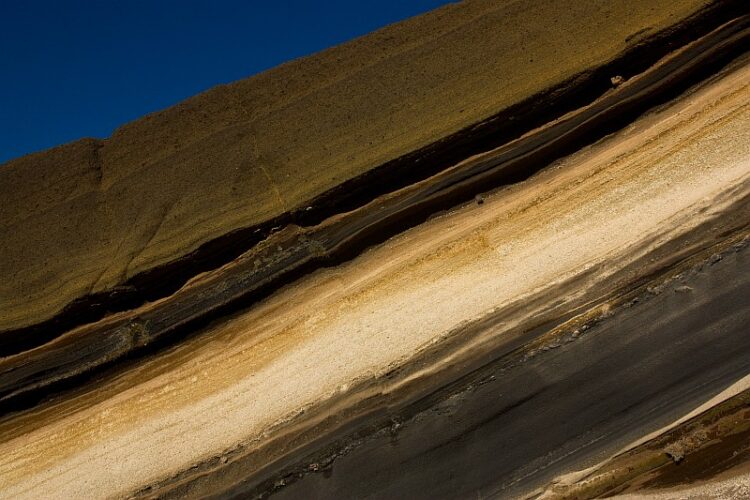 Sequence of pyroclastic rocks in Tenerife. Pumice layer is a product of violent plinian eruption farther away. Scoriaceous mafic dark-colored lapilli were ejected from nearby vents (Strombolian eruptions). Width of view is 12 meters.